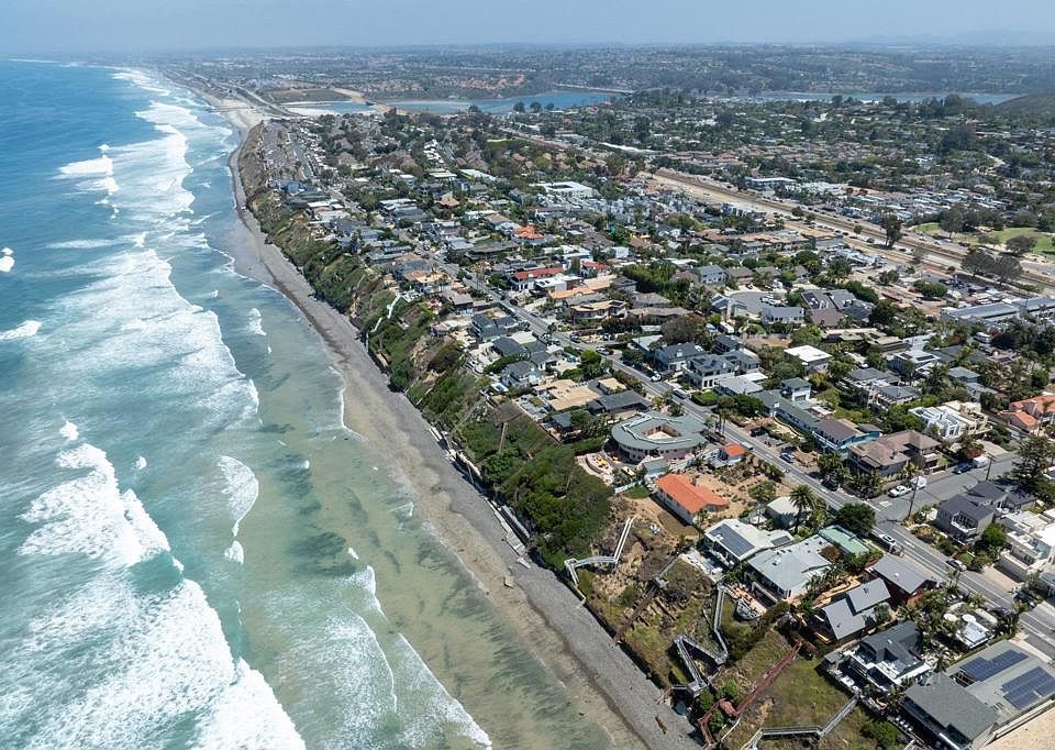 Aerial photograph of the Leucadia coastline in Encinitas: the Pacific Ocean on the left, surfline below the bluffs, and a quiet residential grid along North Coast Highway 101 where 1524 sits among the bluff-side parcels